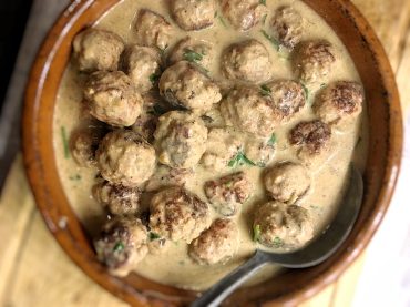Boulettes suédoises maison servies dans une sauce crémeuse aux épices, présentées dans un bol rustique.