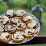 Mini pizzas de courgettes grillées sur le BBQ, garnies de sauce tomate maison, fromage fondu, origan et basilic.