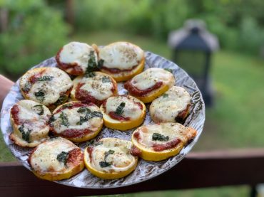 Mini pizzas de courgettes grillées sur le BBQ, garnies de sauce tomate maison, fromage fondu, origan et basilic.