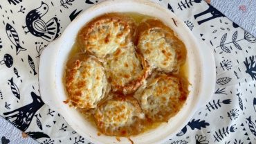 Bol de soupe à l’oignon maison, gratinée au fromage, servie bien chaude avec des croûtons dorés.