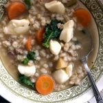 Bol de soupe chaude à l’orge, aux légumes racines, au bœuf et garni de fromage en grains fondant.