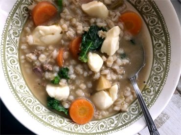 Bol de soupe chaude à l’orge, aux légumes racines, au bœuf et garni de fromage en grains fondant.