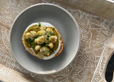 Tartine au chou-fleur grillé et dhal de lentilles corail sur pain naan, garnie d’oignons verts