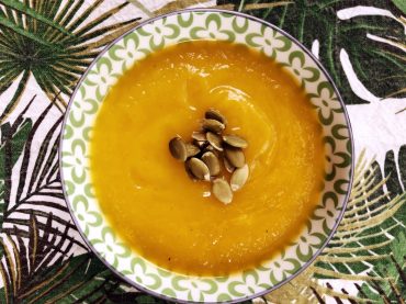 Bol de potage à la courge musquée rôti, servi avec graines de citrouille, yogourt et pain grillé à l’ail.