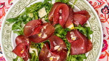 Salade italienne de bébé roquette garnie de fines tranches de bresaola délicatement pliées, de copeaux de parmesan et de zeste de citron.
